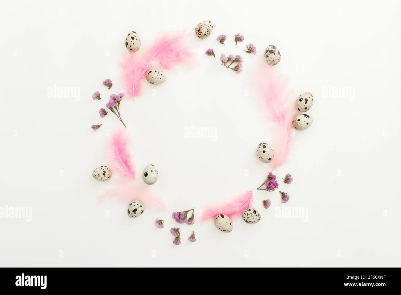 Ester frame composition with quail eggs and pink feathers on white background. Flat lay, top view Stock Photo