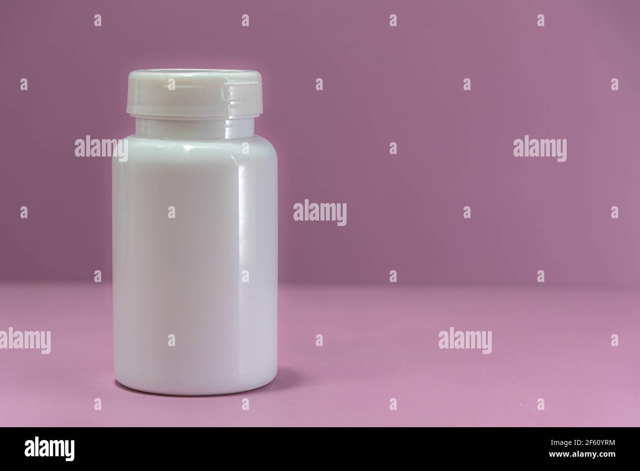 white plastic bottle for medicine on pink background. Medicinal packaging. Bottle for storing pills and pills. Hospital supplies. Stock Photo