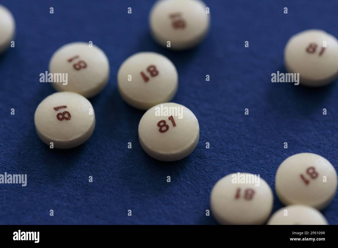 scattered low dose 81 milligrams aspirin on a blue background with a low depth of field, commonly used as a preventive medicine for heart disease with Stock Photo