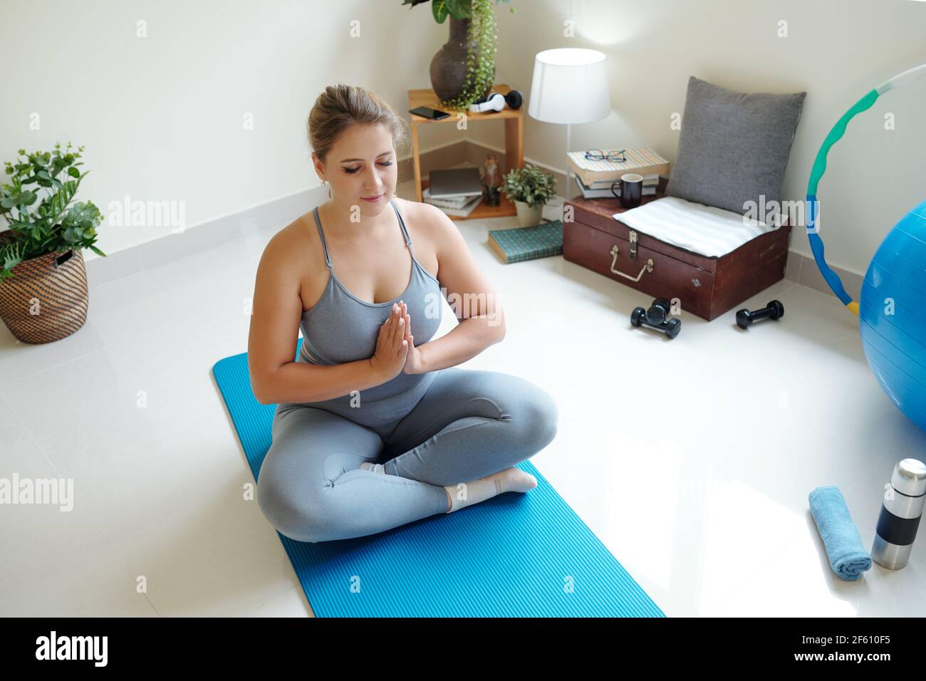 Beautiful young plus size woman meditating on yoga mat with her eyes closed  Stock Photo - Alamy