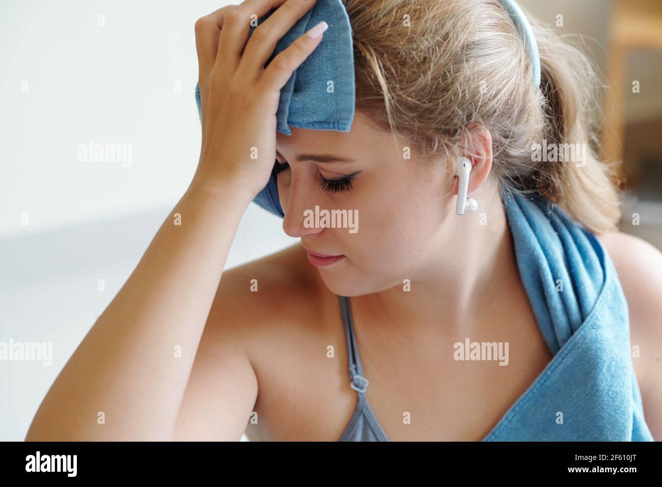 Tired young woman wiping sweat off her forehead after intense training at home Stock Photo