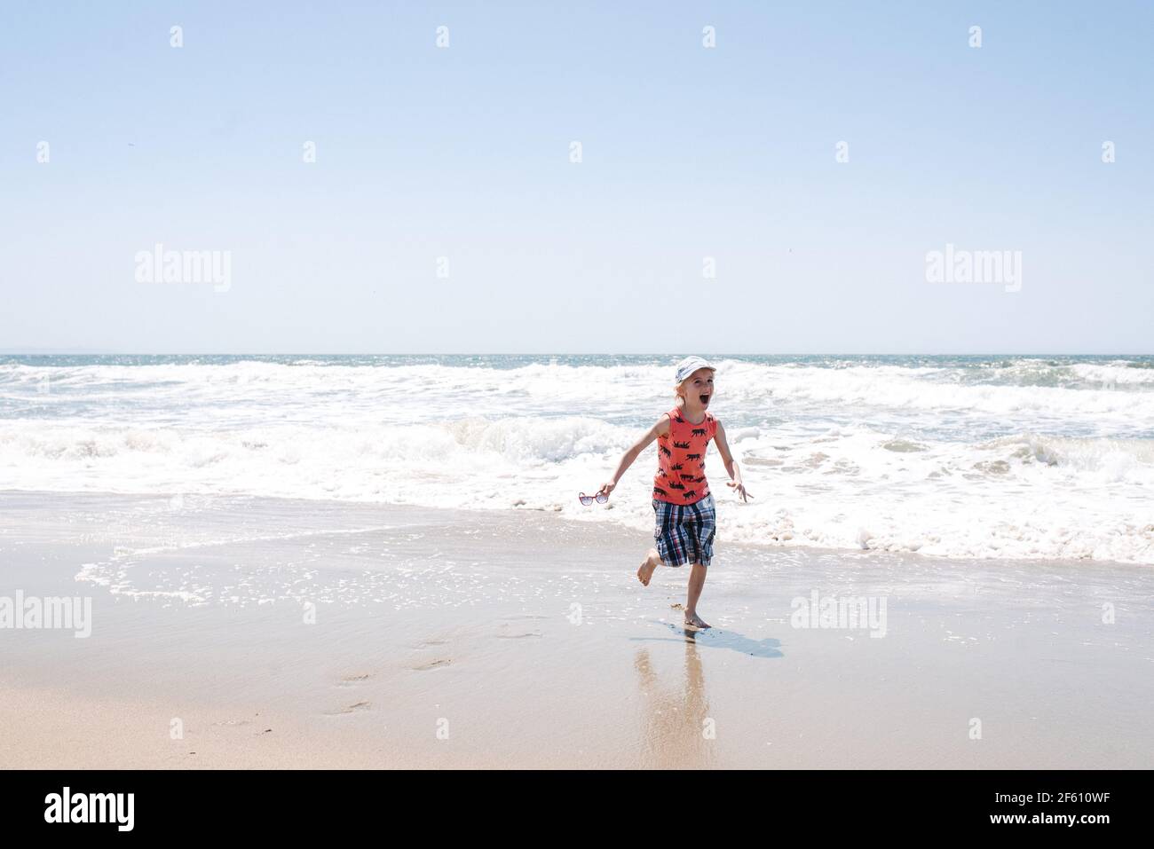 Boy by the sea, running from waves Stock Photo