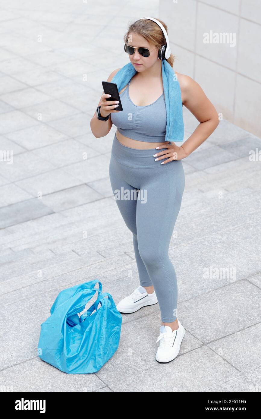 Pretty plus size fitness blogger standing after and answering comments on social media Stock Photo - Alamy