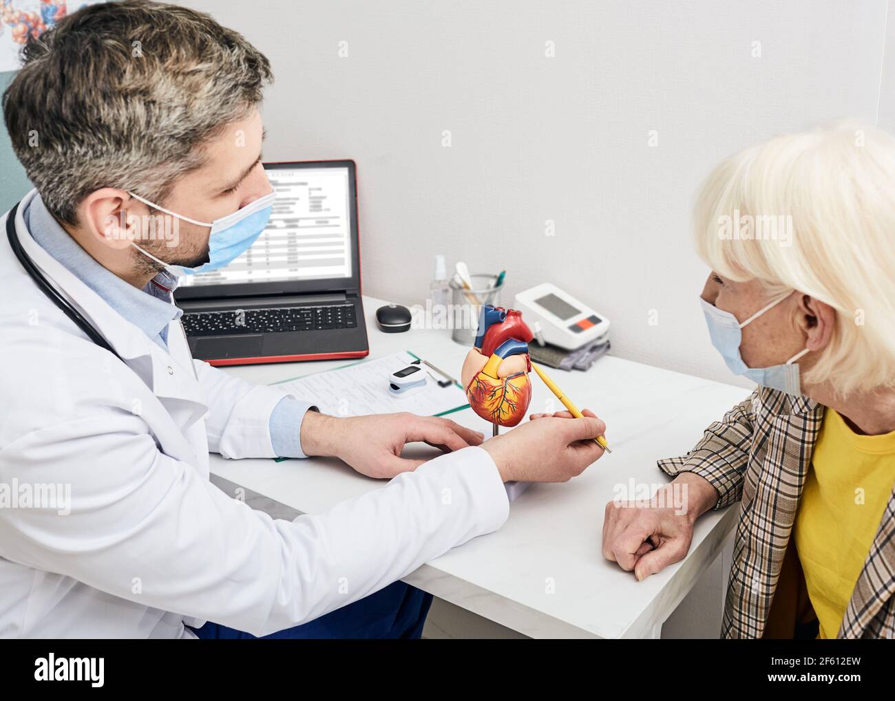 doctor shows to older patient heart anatomy during a visit to the clinic. Consultation with a cardiologist Stock Photo