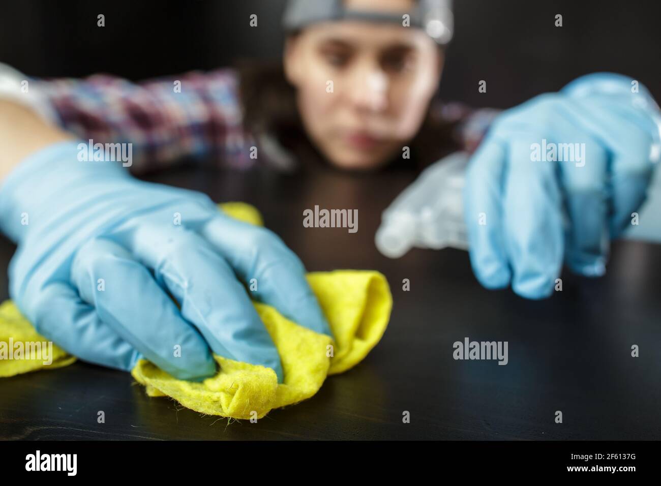 Female hands in rubber gloves with a rag spray detergent and wipe the table from dust and dirt. Housework. Cleaning of premises.  Stock Photo