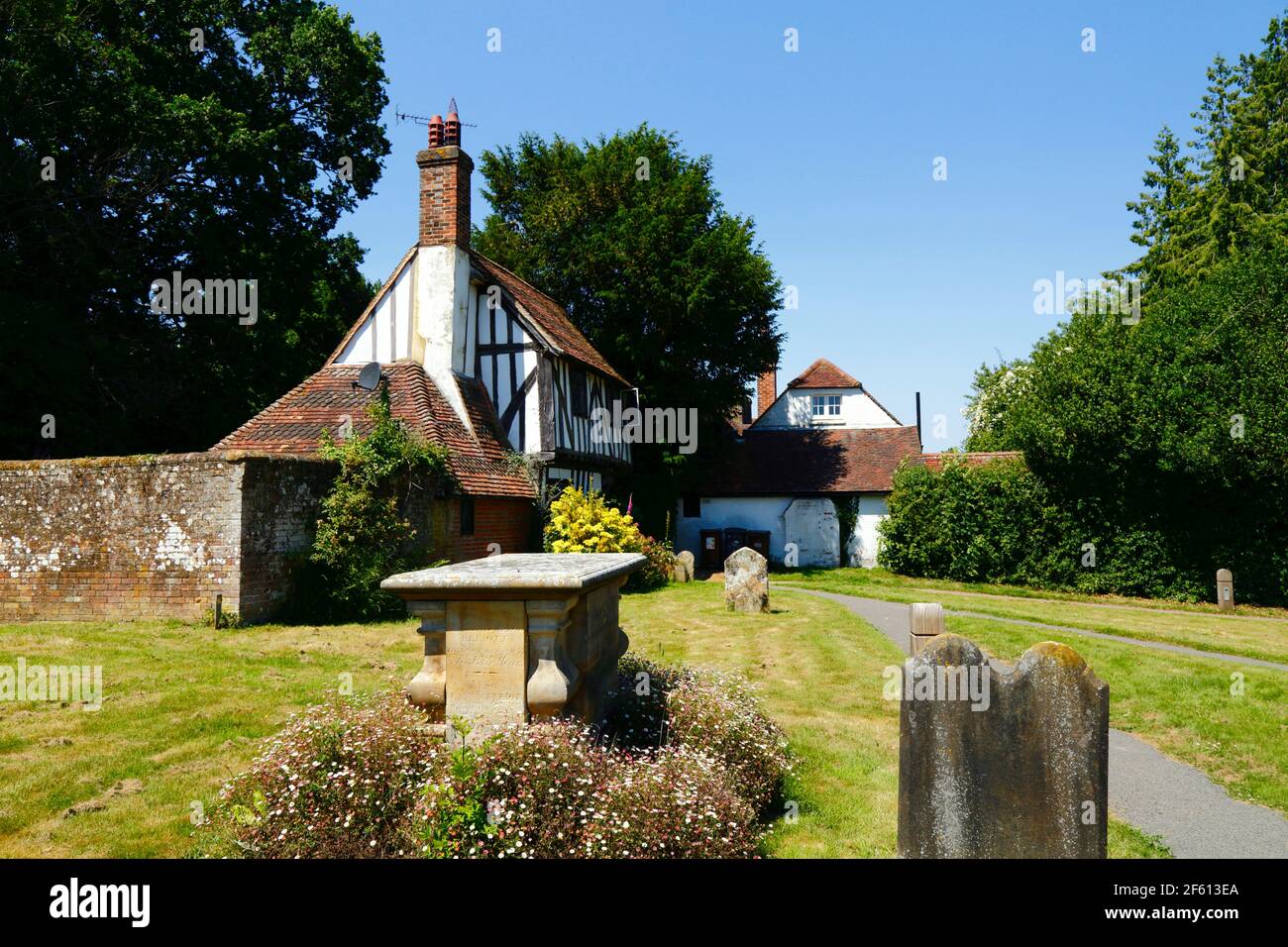 Chest tomb of Elliott family and historic timber framed cottage at entrance to St Mary the Virgin churchyard, Hartfield, East Sussex, England Stock Photo