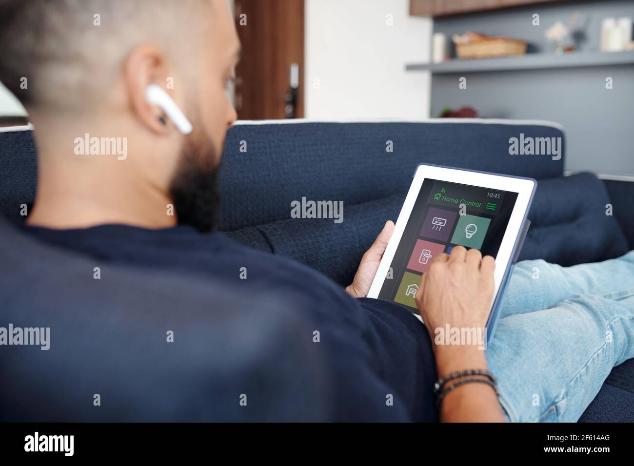 Close-up image of man using home control application on digital tablet when resting on sofa Stock Photo