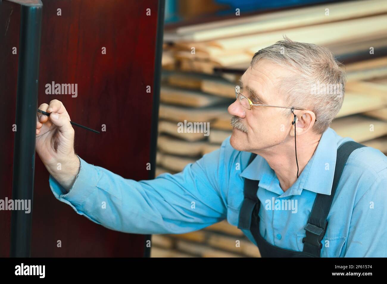 Portrait of an elderly carpenter at work in a carpentry shop. Stock Photo