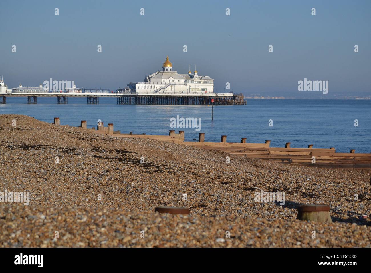 Eastbourne Stoney Beach Looking Towards Eastbourne Pier On A Sunny Winters Day - Blue Sky And Calm Sea - Wooden Groynes English Channel - Sussex UK Stock Photo
