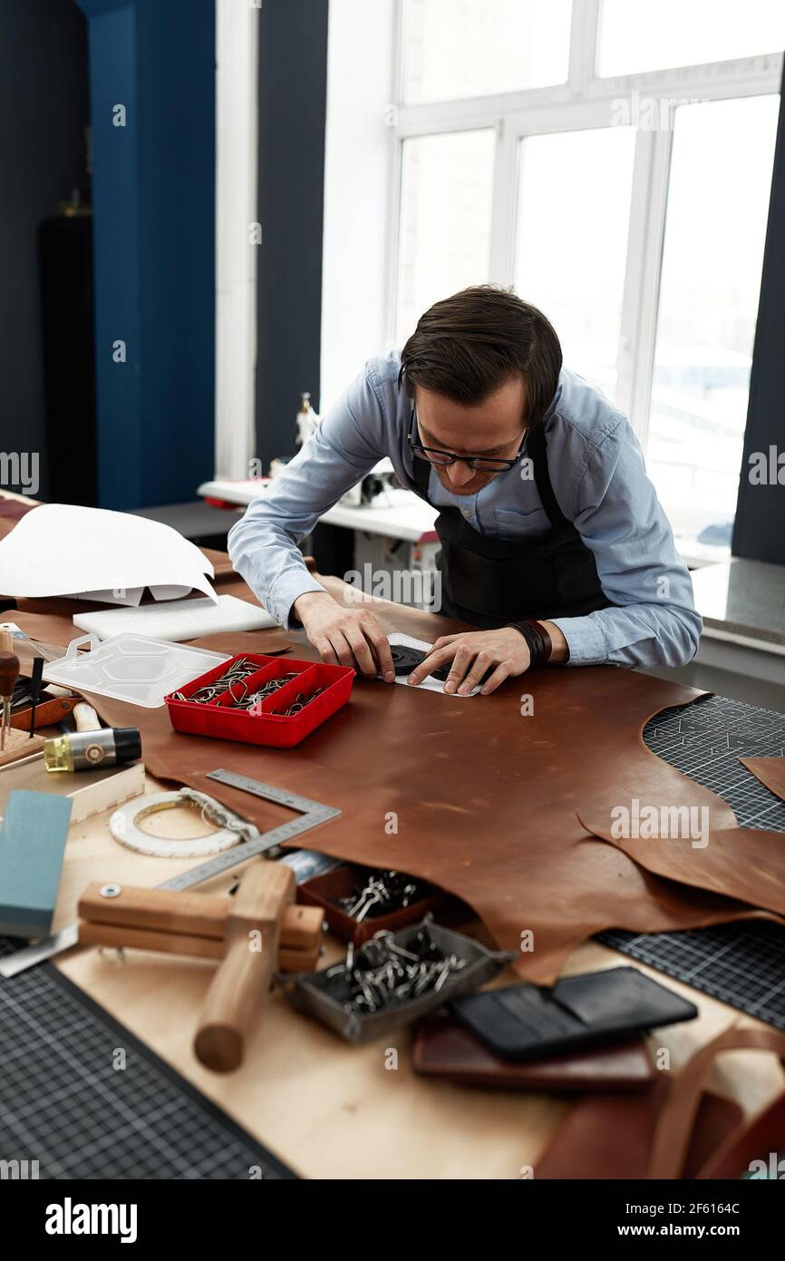 Skilled leather manufacture worker cutting some samples. Stock Photo