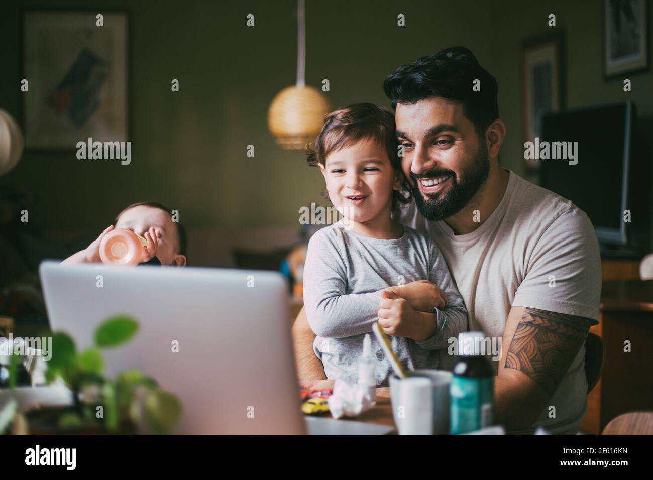 Smiling son and father taking online advice through laptop at home during pandemic Stock Photo