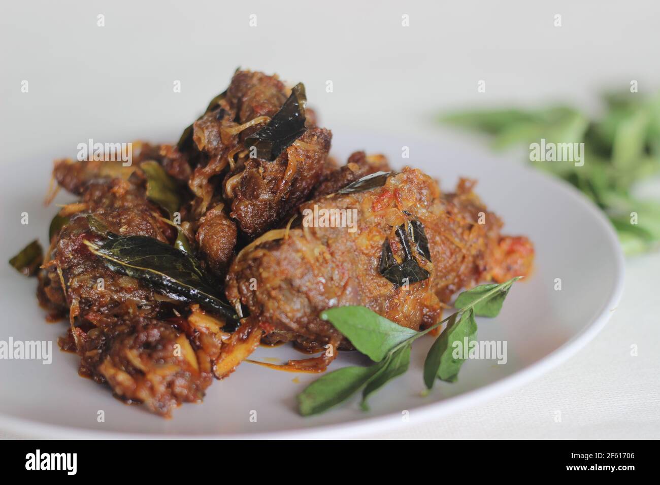 Kerala style mutton roast prepared with coconut oil. Shot on white background Stock Photo