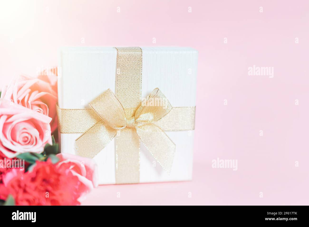 Beautiful bouquet of roses with gift against pink background. Free space for text Stock Photo