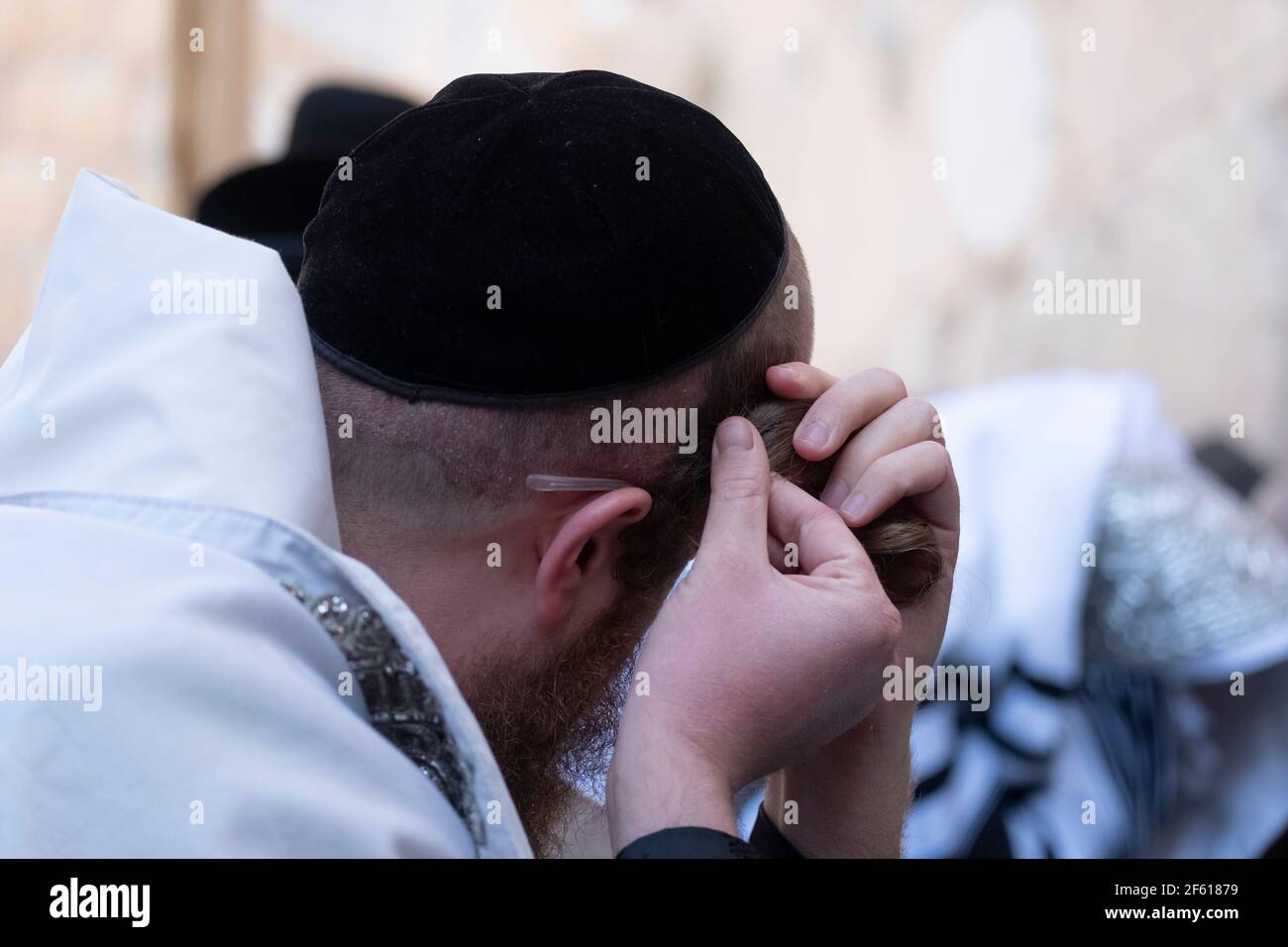 A Haredi Jew curling his twisted payot sidelocks as he prays in the Western Wall in Jerusalem Israel Stock Photo