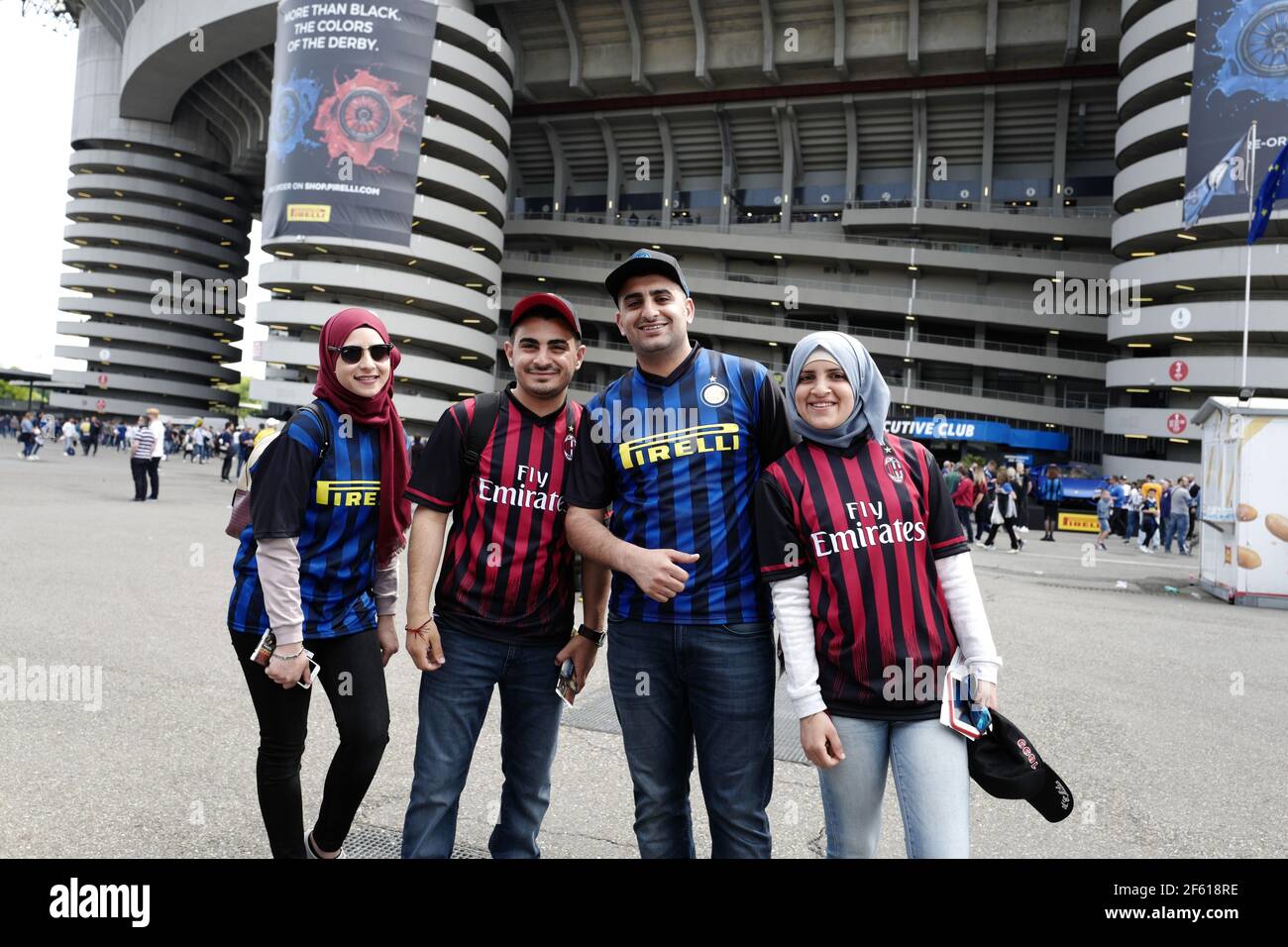 Young couples from Middle East wearing AC Milan and Inter Milan football uniforms outside the Giuseppe Meazza stadium, in Milan, Italy. Stock Photo