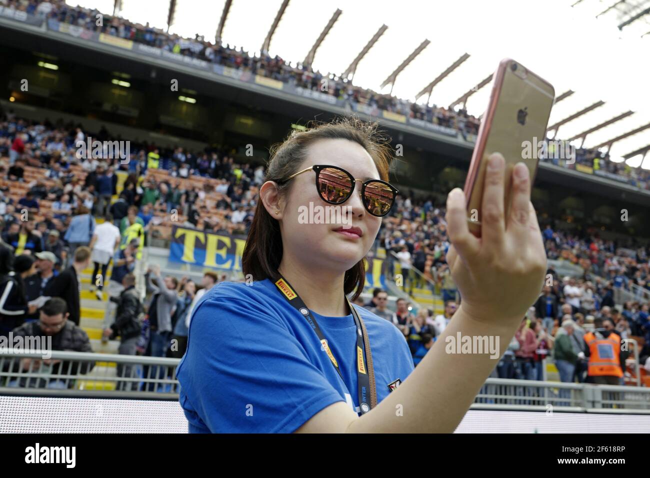 Chinese girl Inter Milan's football fan taking a selfie portrait with an iPhone  at the san siro football stadium, in Milan. Italy. Stock Photo