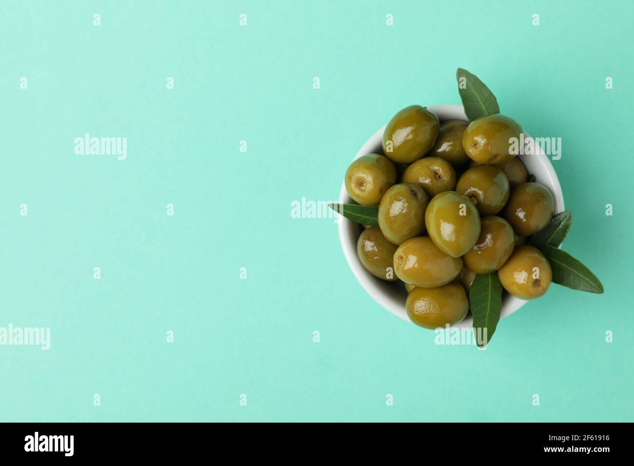 Bowl of green olives and leaves on mint background Stock Photo Alamy