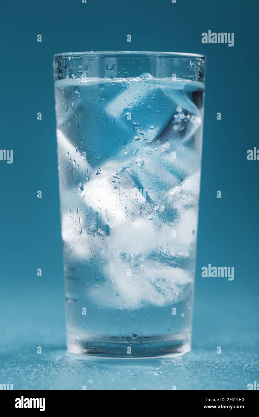 Ice cubes in a glass with crystal clear water on a blue background ...