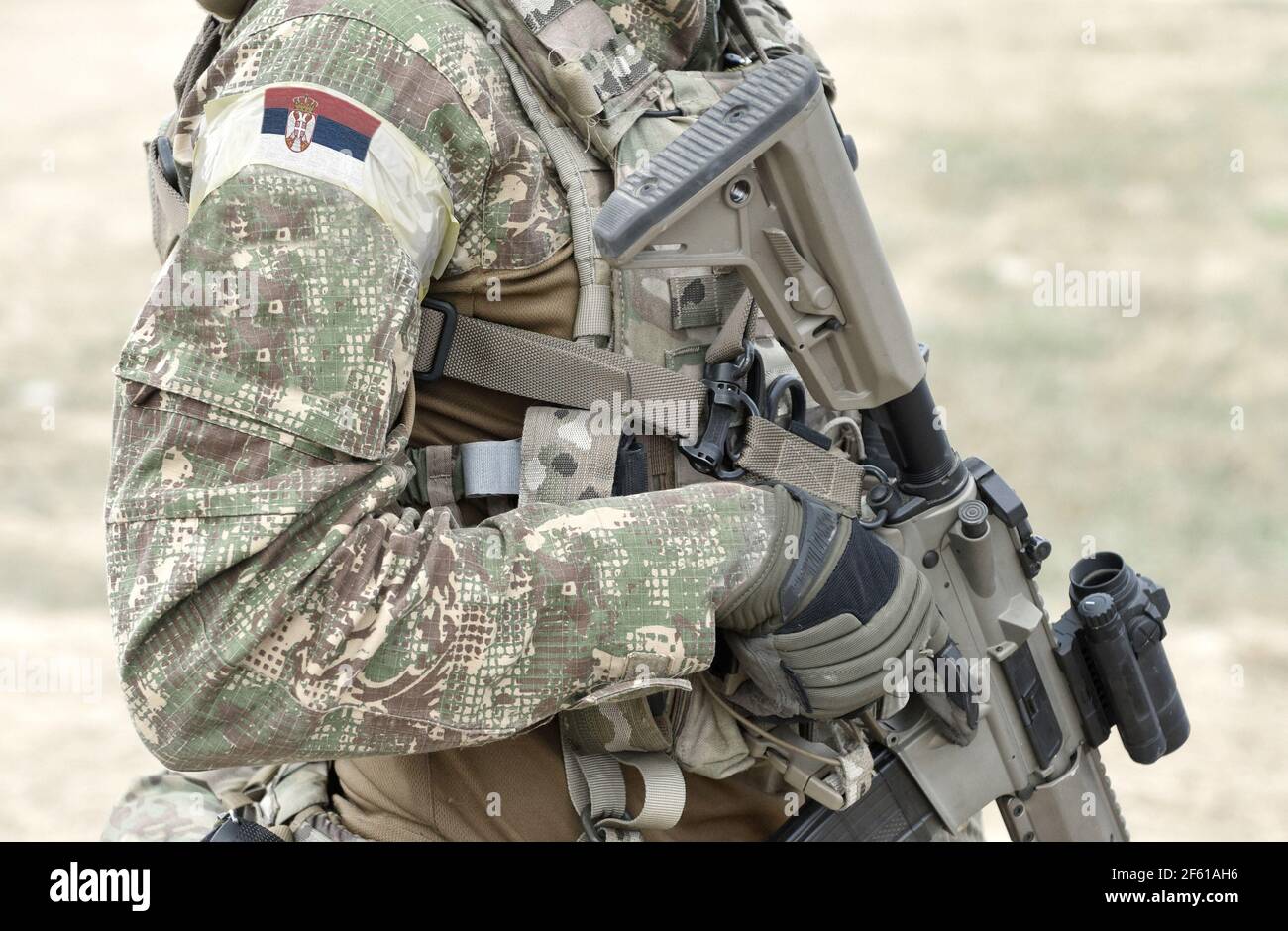 Soldier with assault rifle and flag of Serbia on military uniform. Collage. Stock Photo