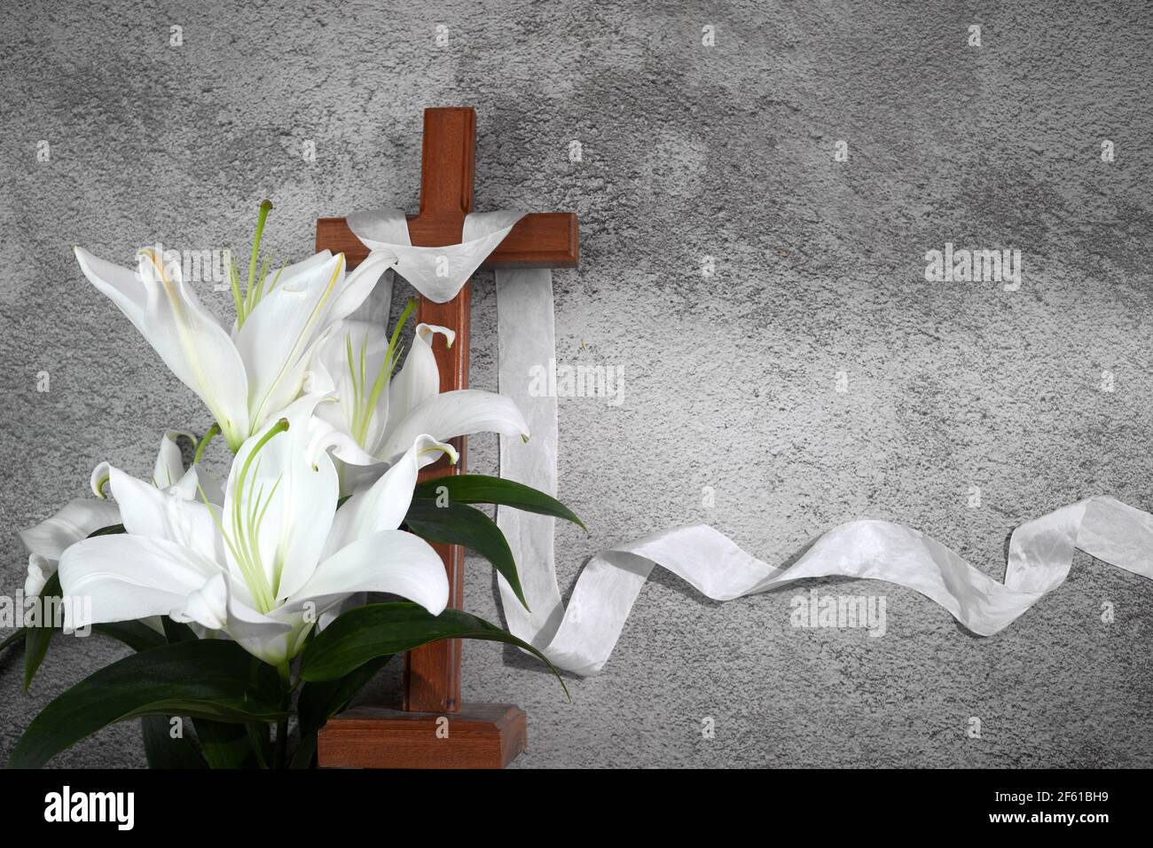 Cross with white lilies on grey background. Catolic Ester concept. Stock Photo