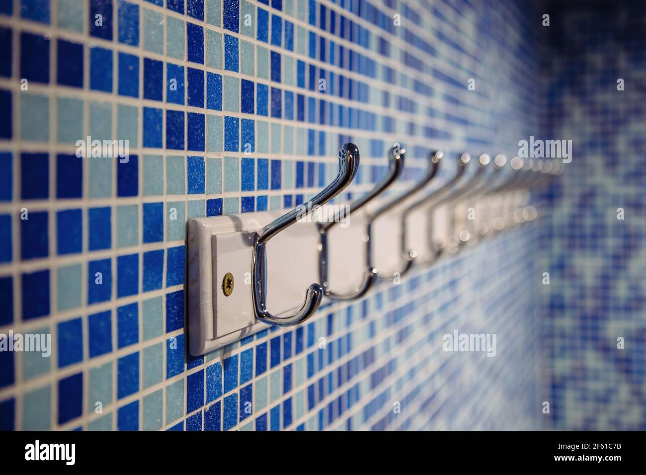 Metal hanger hooks on blue tiled wall. Stock Photo