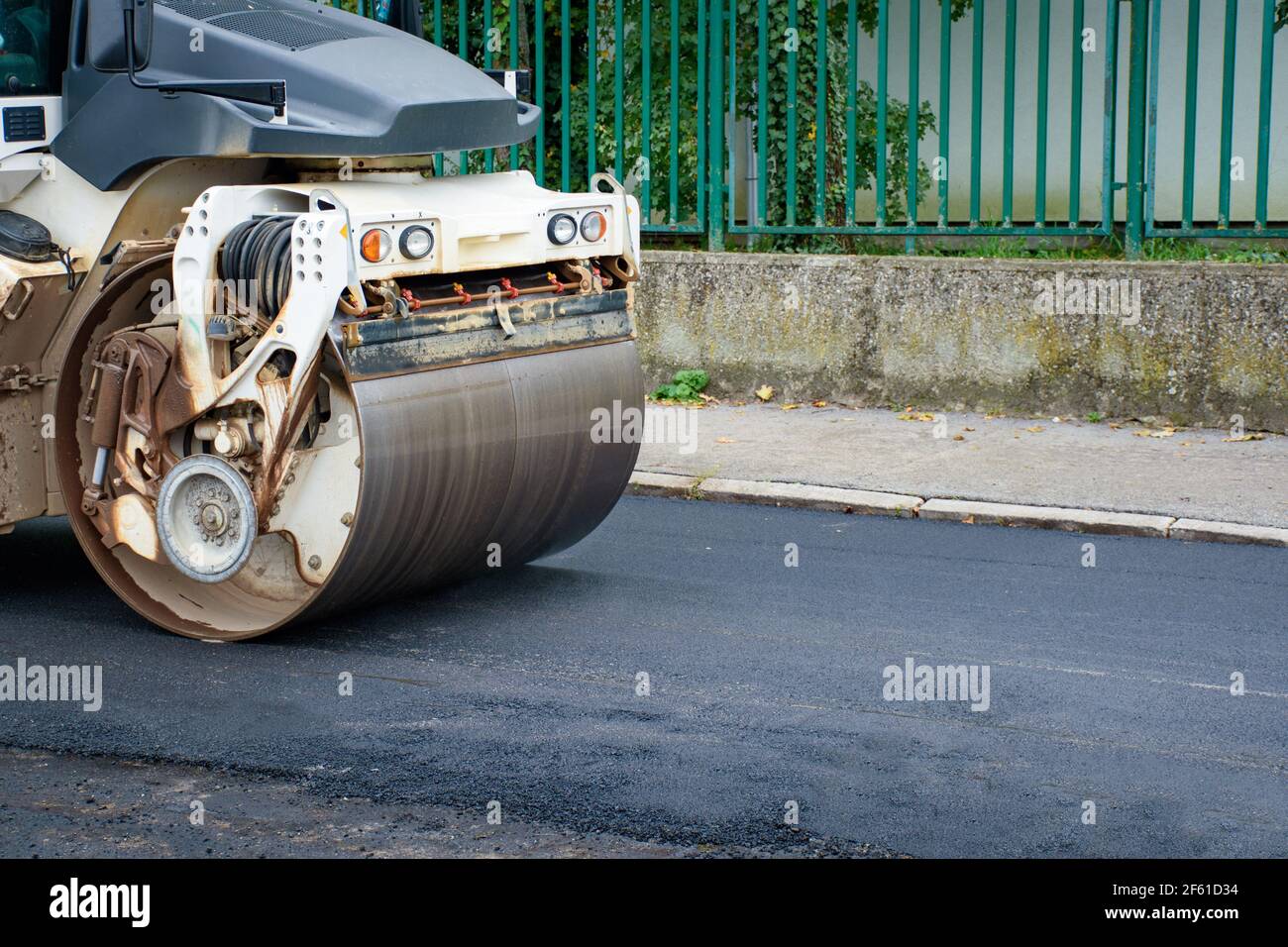 Main front wheel of Asphalt Roller compacts new asphalt in reconstruction of road Stock Photo