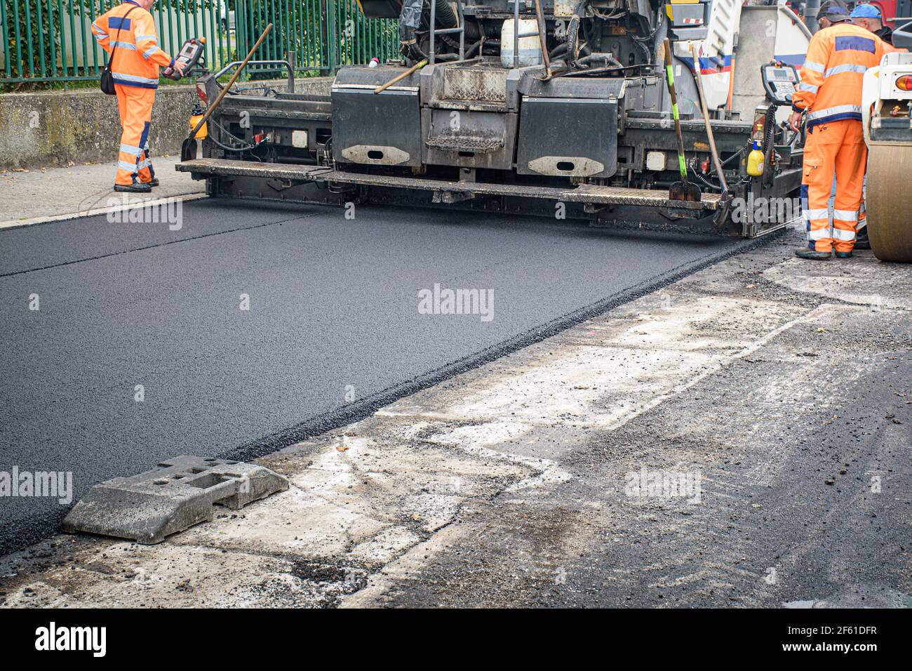 Screed of asphalt paver makes smooth asphalt mat - road reconstruction Stock Photo