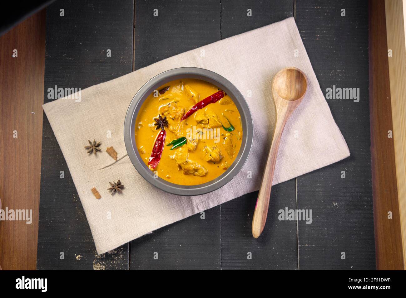 Chicken with raw banana curry (plantain),spicy chicken with green banana tastier indian dish arranged in a tableware which is on a tissue with black b Stock Photo