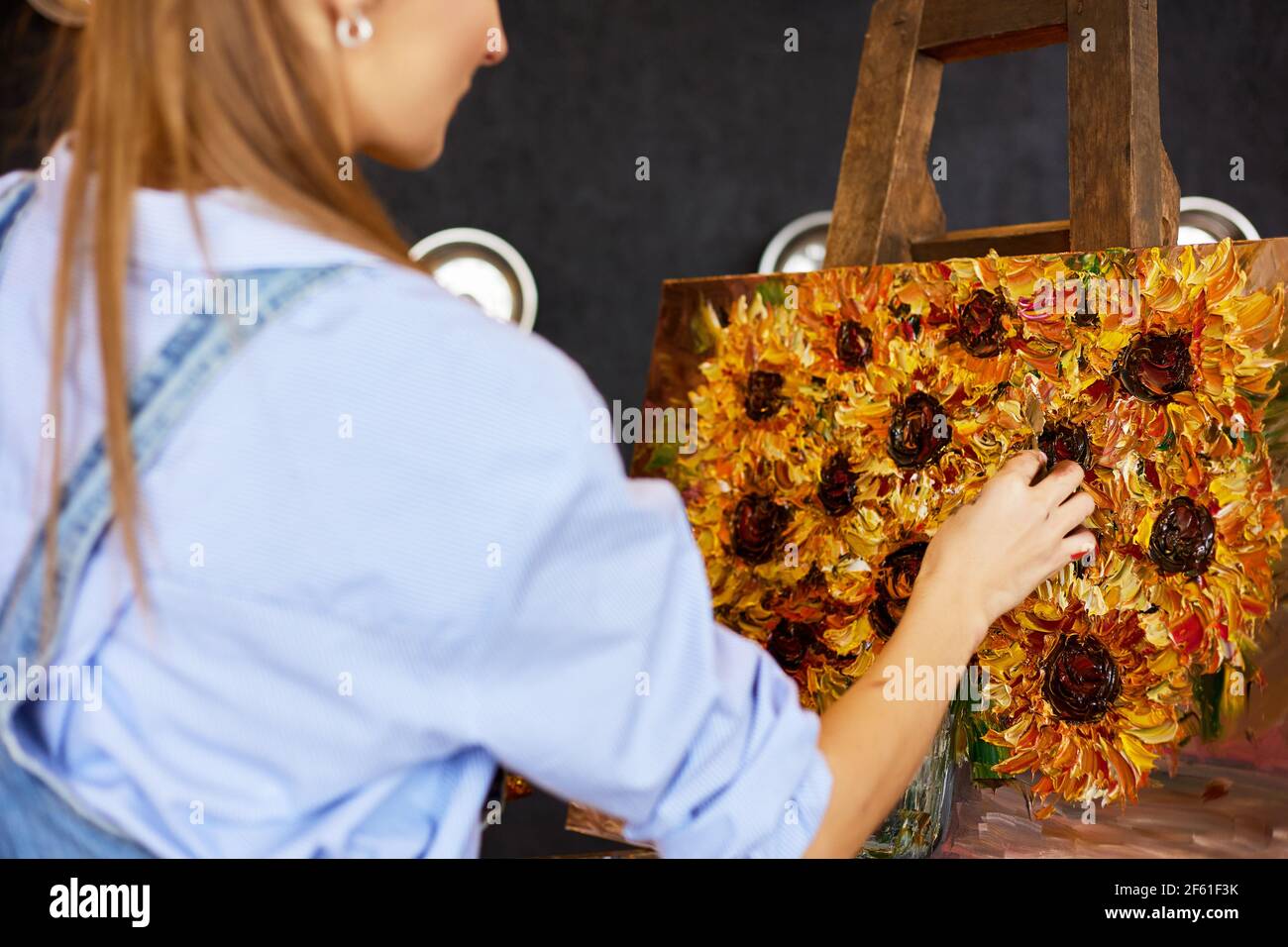 Young beautiful female artist painting still life with sunflower on ...