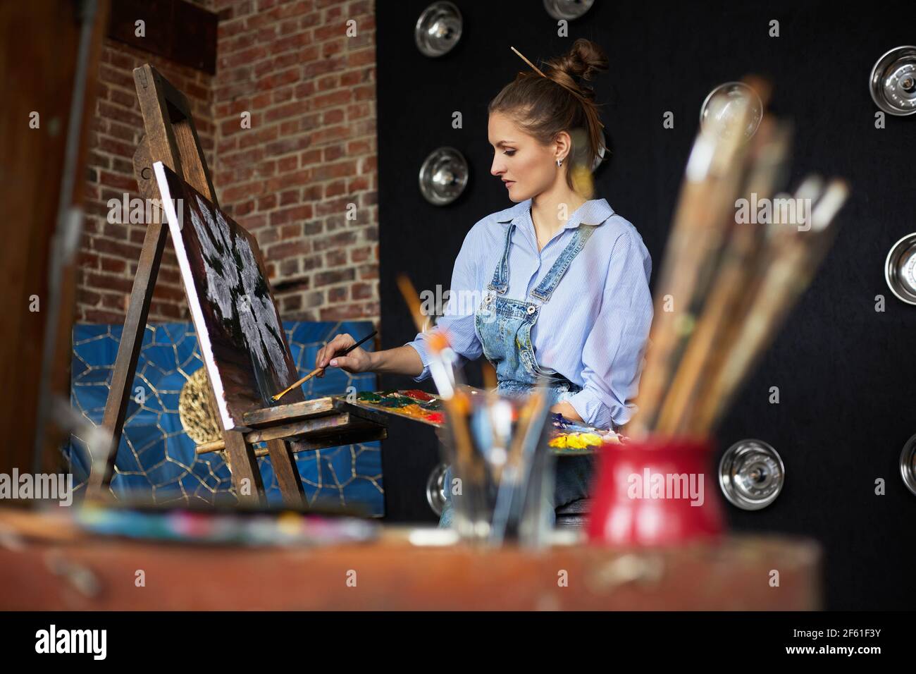 Young beautiful female artist painting still life with sunflower on ...