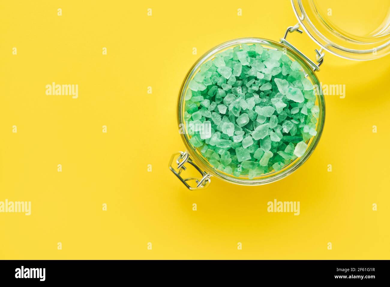 Green aroma bath salt in a glass jar on yellow background. Spa, skincare concept. Top view, copy space. Selective focus Stock Photo