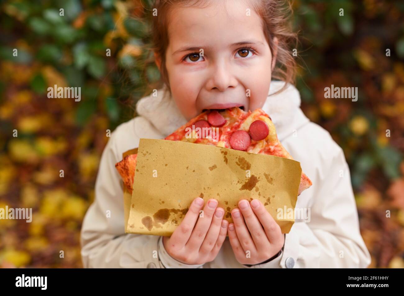 little girl eating pizza. Person holds pizza in hands and eats in the