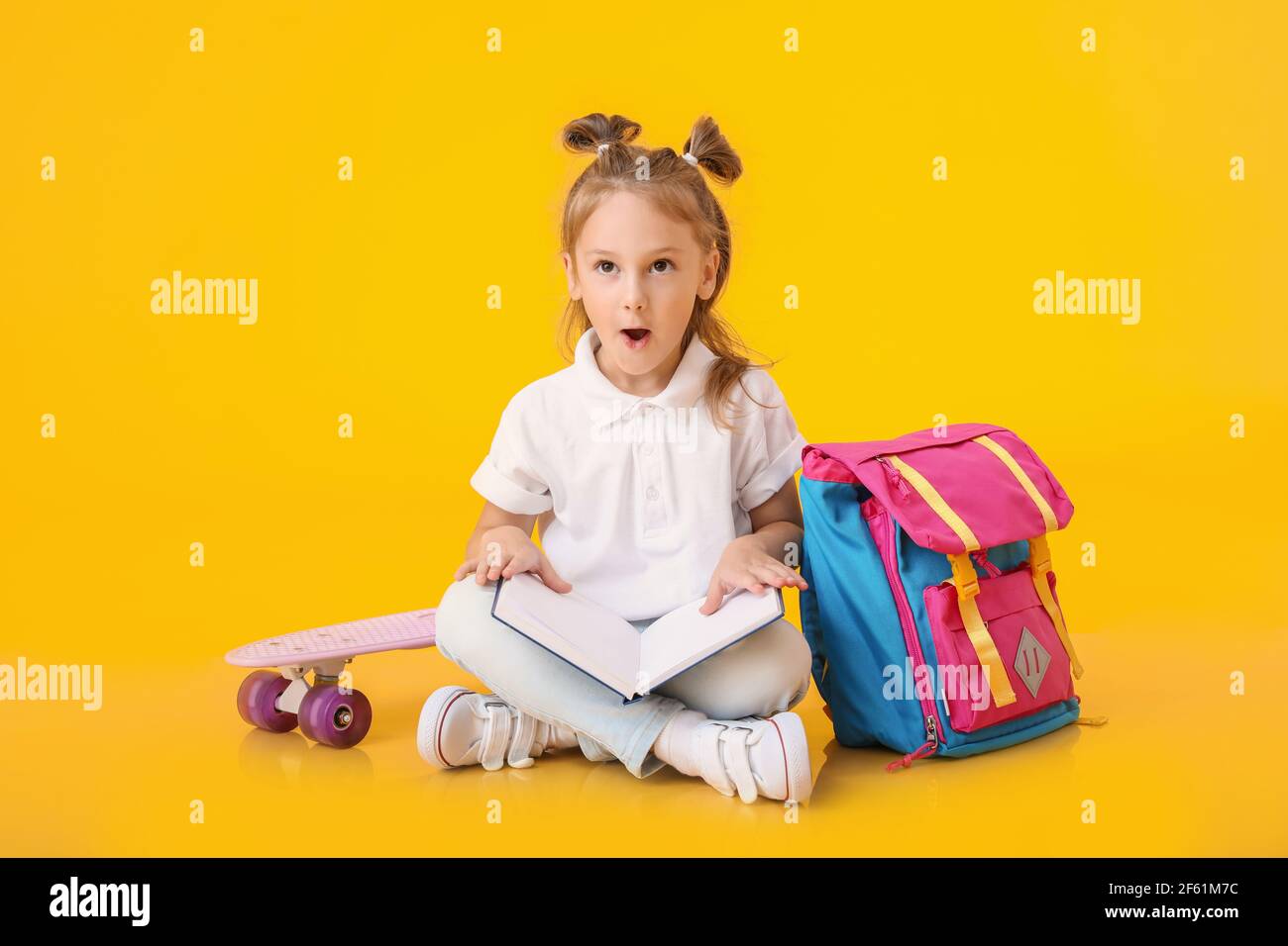 Surprised little schoolgirl with book on color background Stock Photo ...