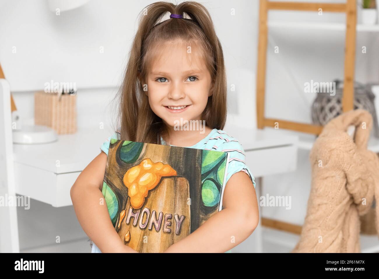 Cute little girl with book at home Stock Photo - Alamy