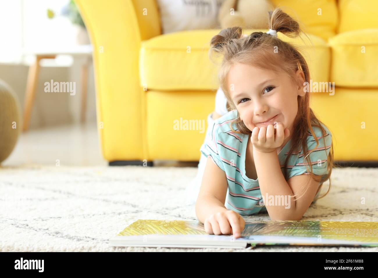 Cute little girl reading book at home Stock Photo - Alamy