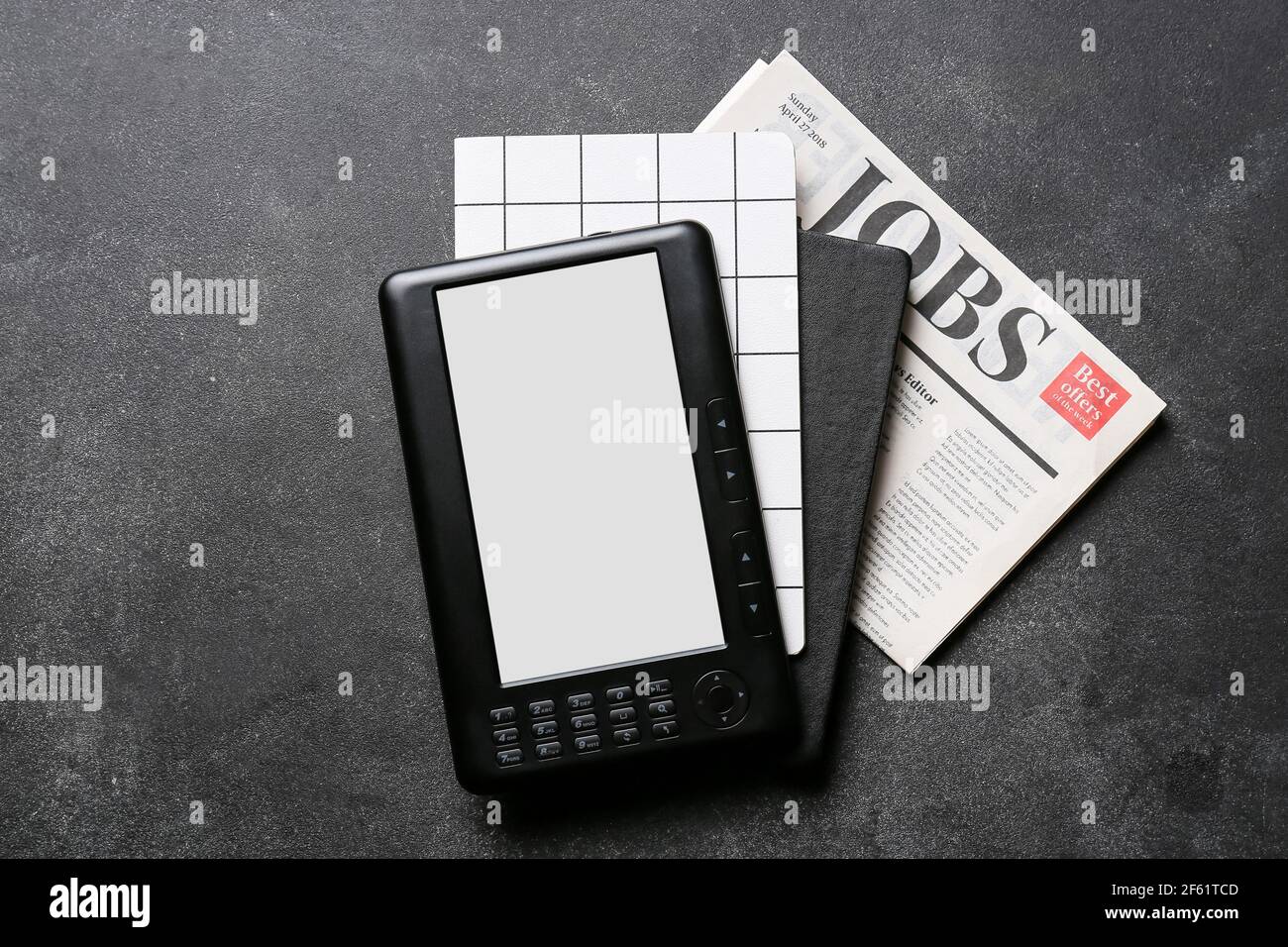 Ereader with notebooks and newspaper on dark background Stock Photo