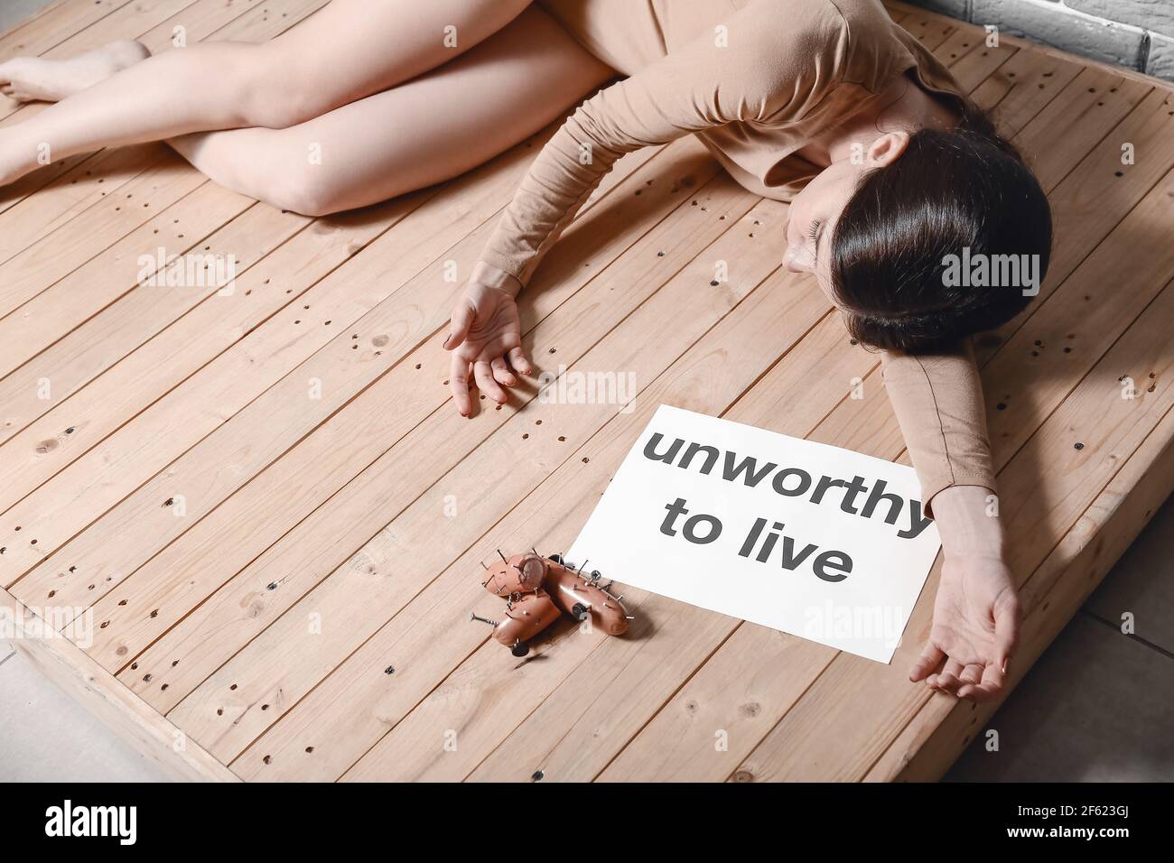 Young woman lying on floor near sausages with nails. Concept of cruelty to animals Stock Photo