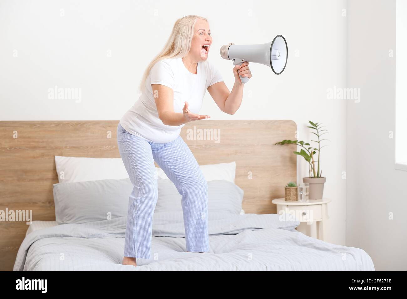 Screaming mature woman with megaphone at home Stock Photo
