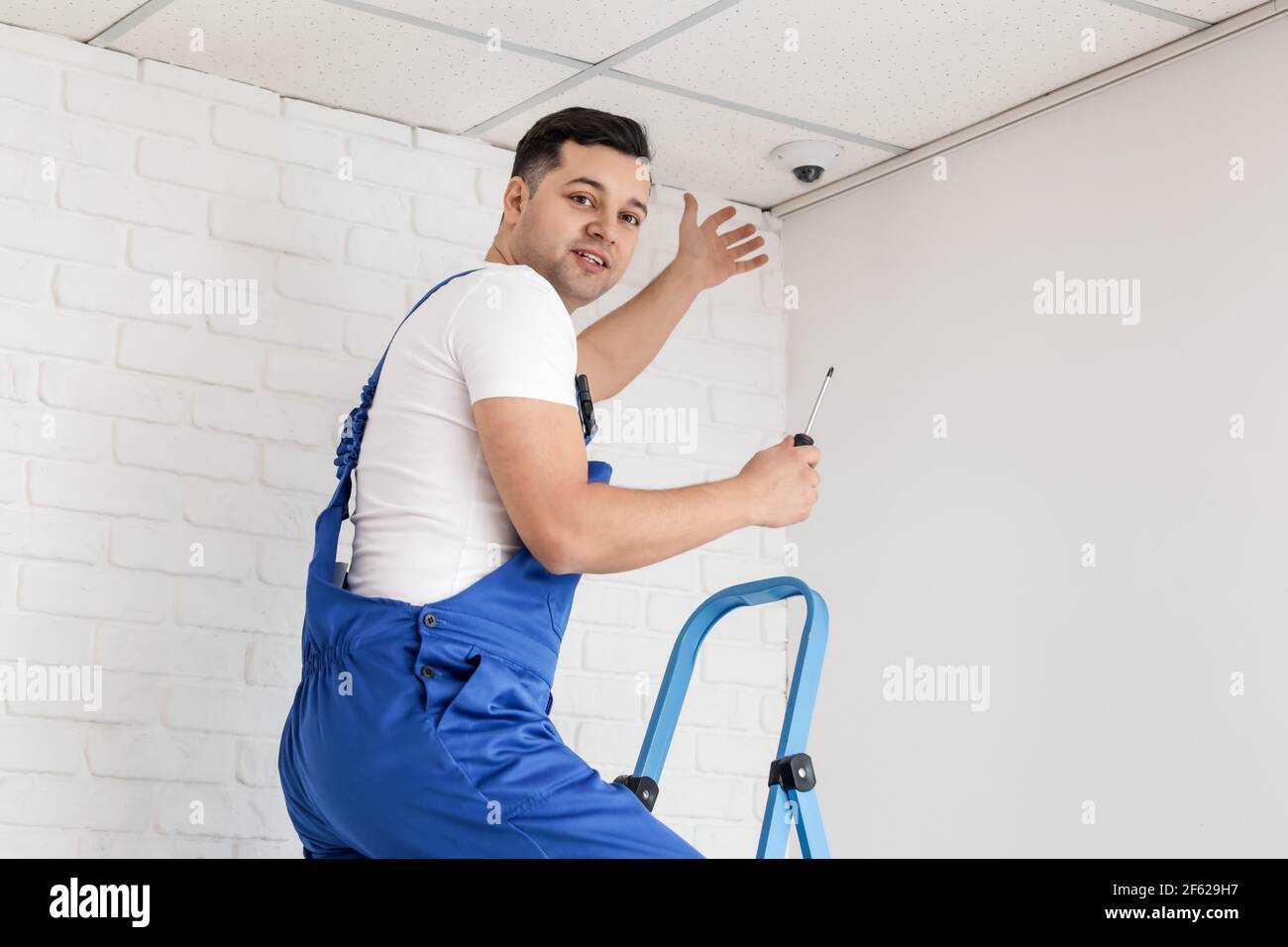 Worker installing CCTV camera in room Stock Photo
