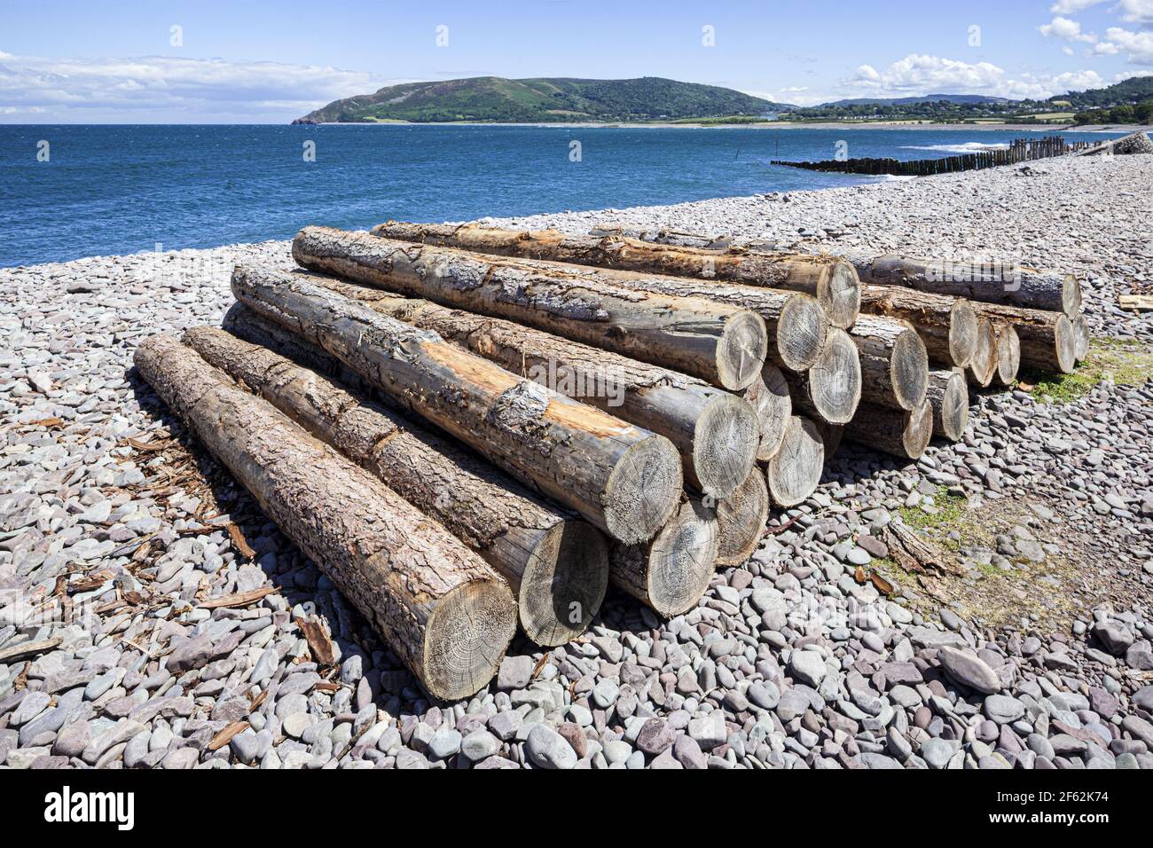 Timber logs on the pebble beach beside the harbour on the edge of Exmoor at Porlock Weir, Somerset UK Stock Photo