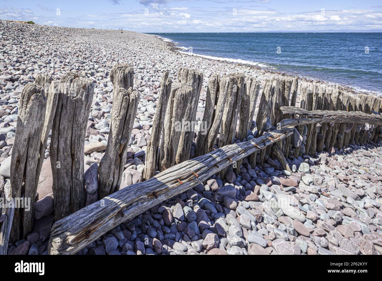 An old wooden groyne (breakwater) on the pebble beach beside the harbour on the edge of Exmoor at Porlock Weir, Somerset UK Stock Photo