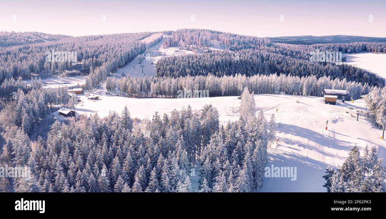 Air view on the winter sports slopes at the ski lift carousel Winterberg. Sledding slope and ski slopes between snow covered spruce forests. Stock Photo