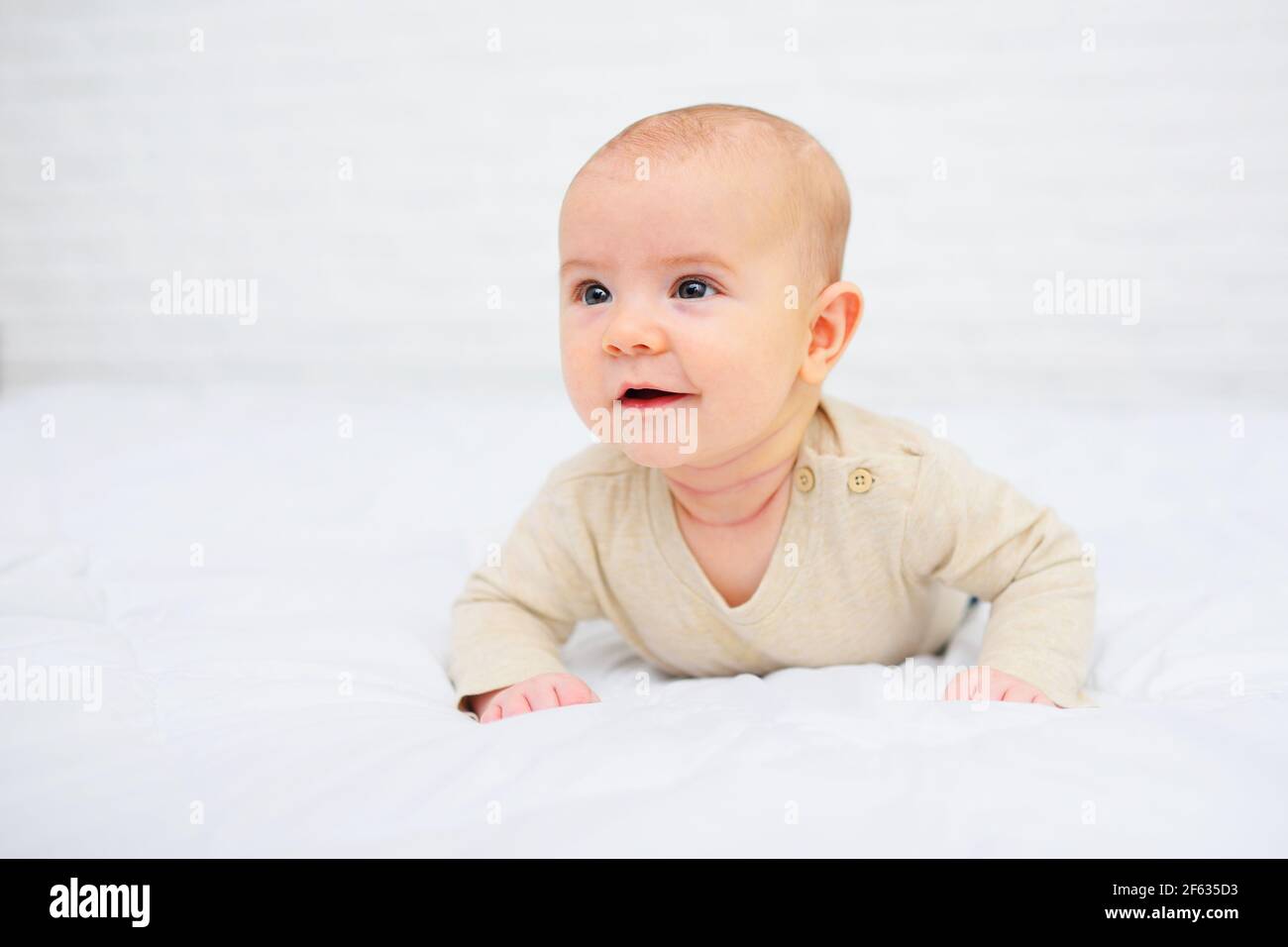 baby is lying on his stomach and smiling on a white background Stock ...