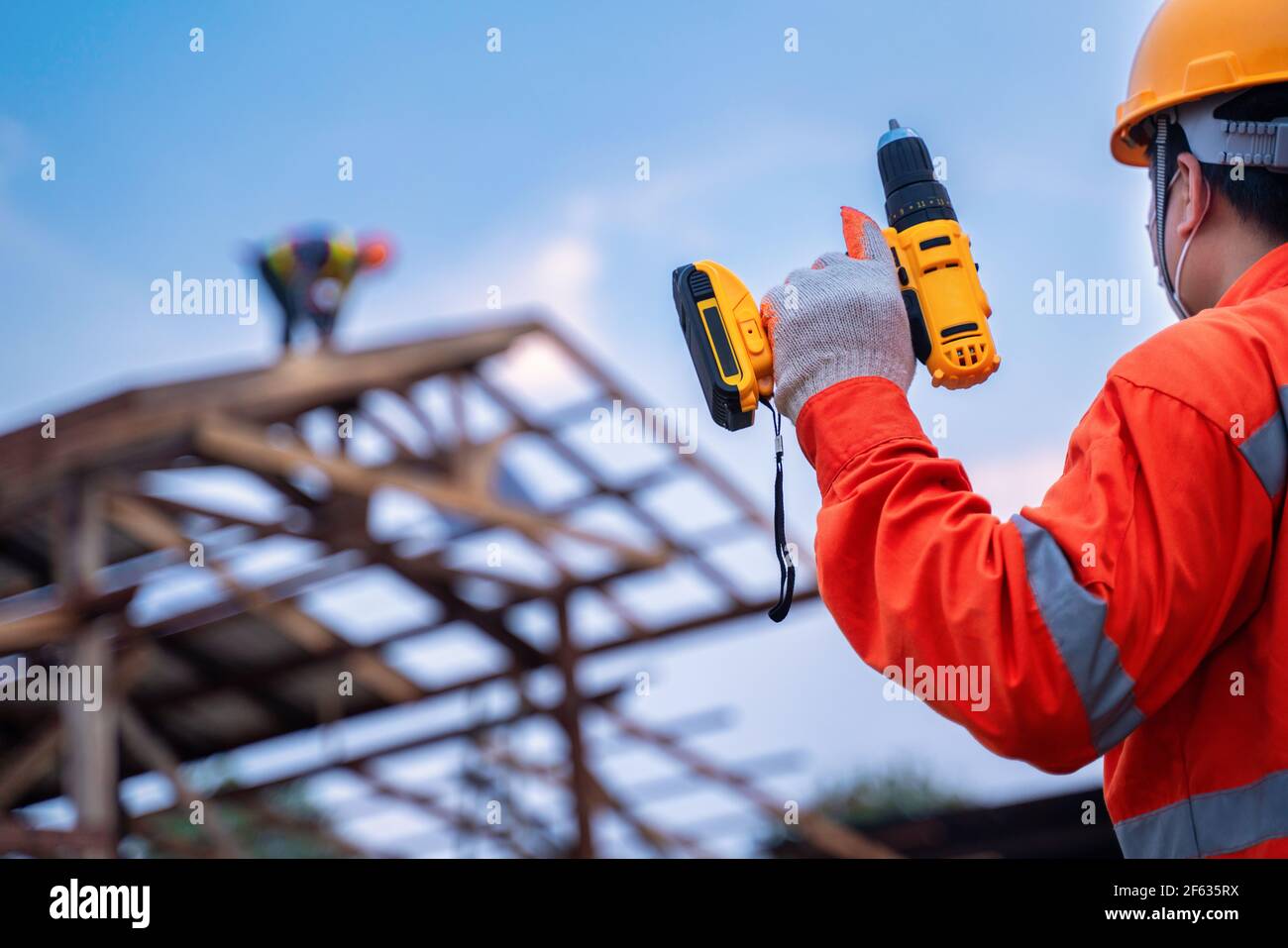 Roofing tools, Roofer worker holding electric drill used on new roofs with Metal Sheet at