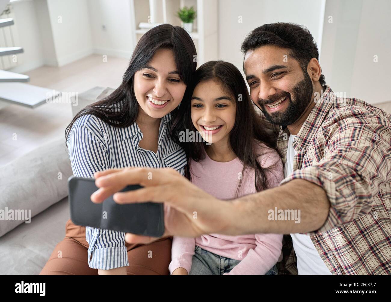 Happy indian family with teen daughter having video call on phone at home. Stock Photo