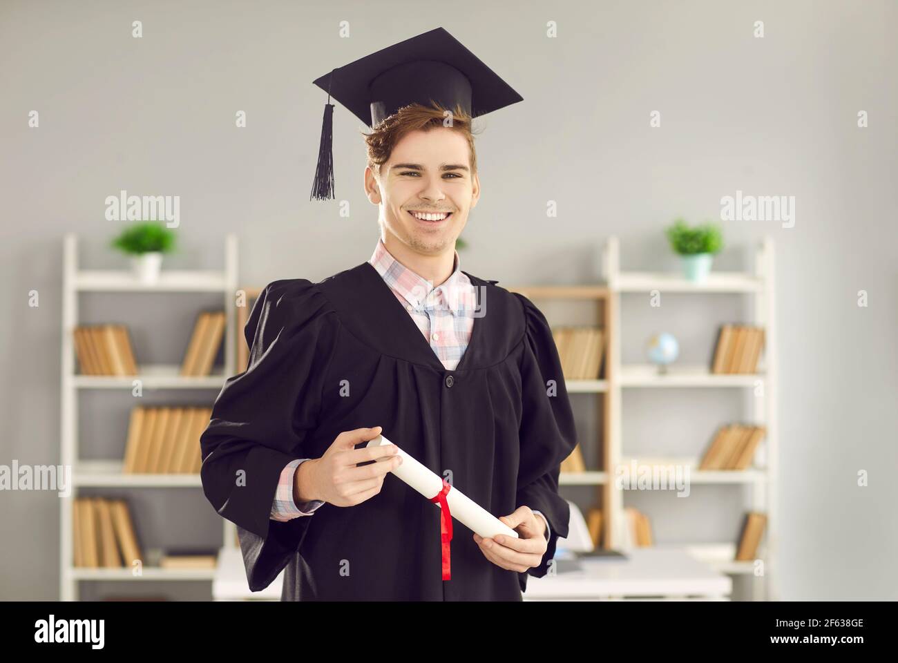 Graduate student in gown, hat with graduation certificate diploma portrait Stock Photo