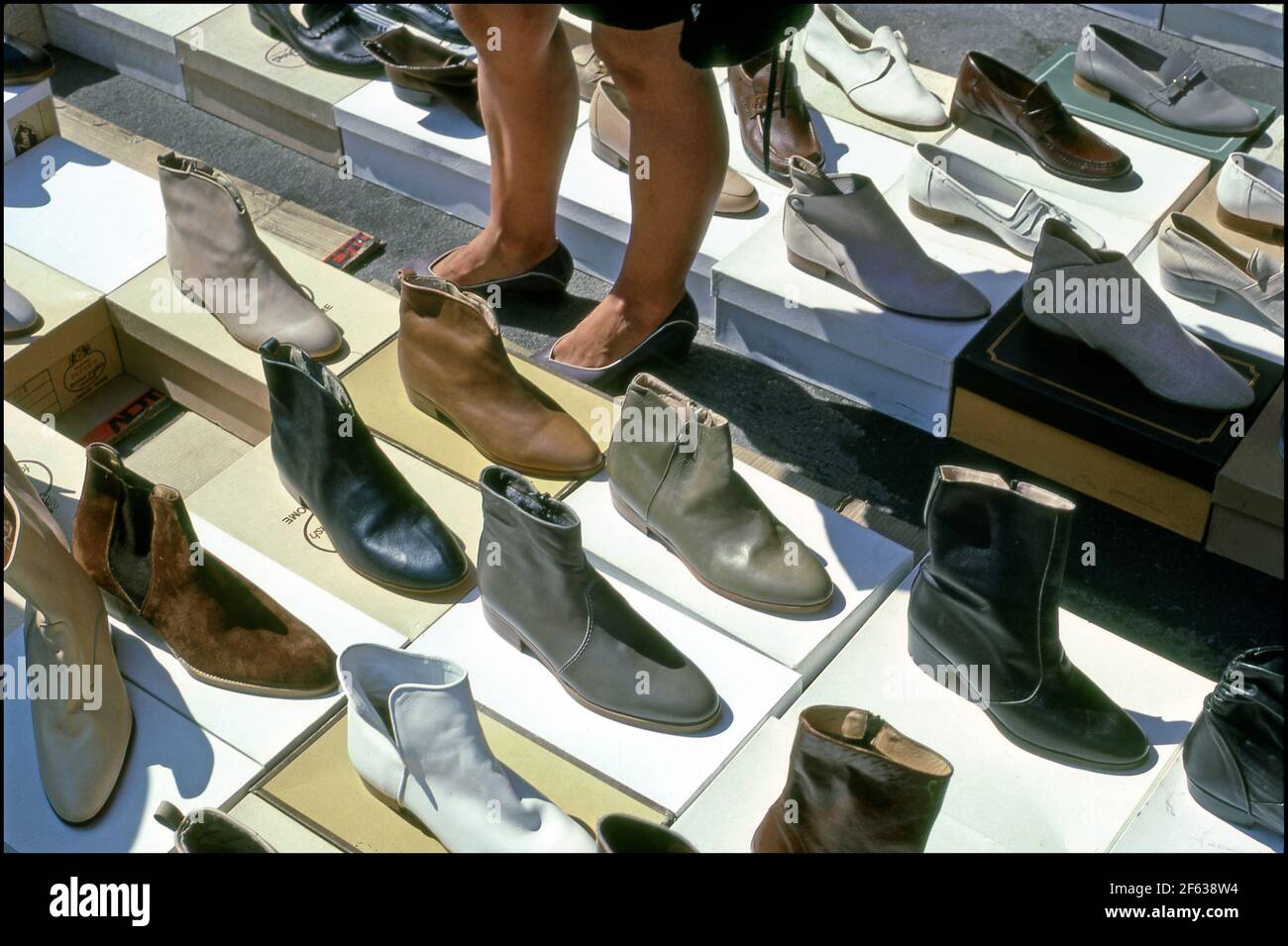 Woman looking at shoes displayed on the ground of an outdoor market in Arezzo, Italy. Stock Photo