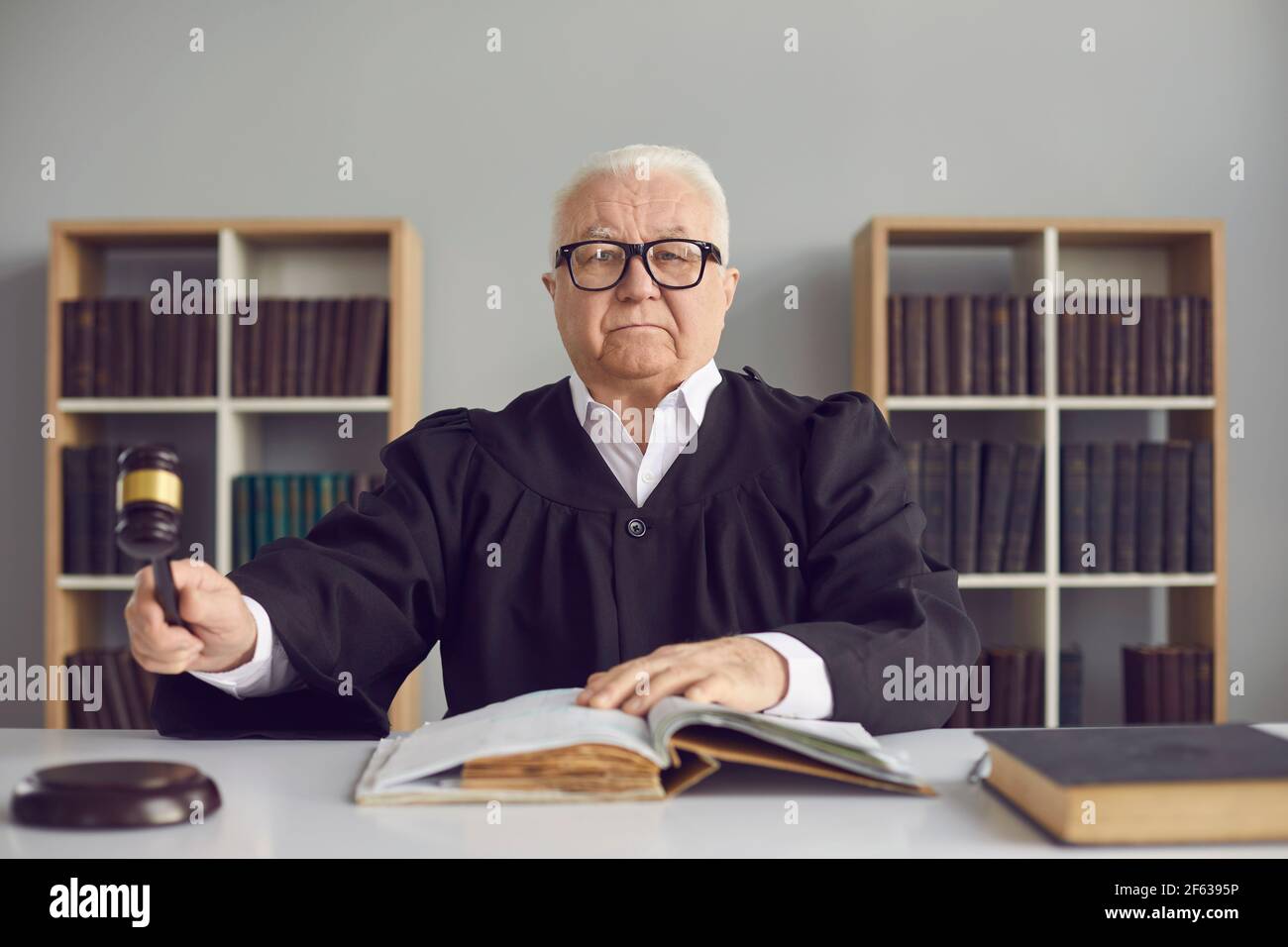 Mature judge knocking with a hammer passing sentence and announcing that the case will be closed. Stock Photo