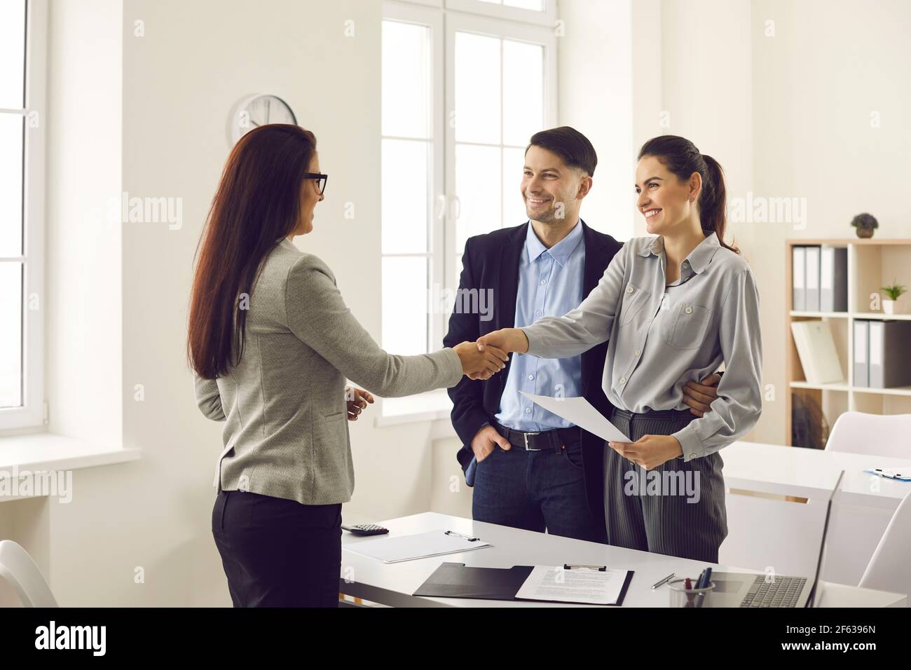 Young smiling couple shaking hands with real estate agent or bank manager Stock Photo