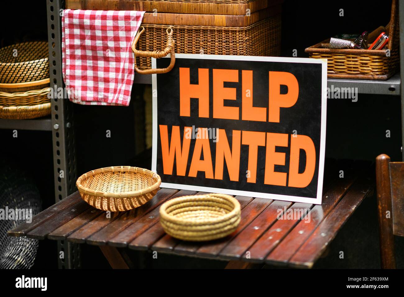 Help Wanted sign displayed in a shop selling woven baskets in a job vacancy, hiring and employment concept Stock Photo